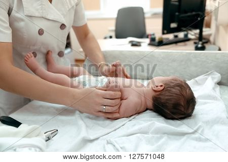 Pediatrician examining littlle newborn baby on the table