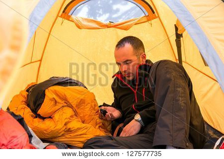 Man lying on Sleeping Bag and Checking Oxygen Content in His Body