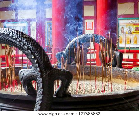 Buddist temple, Singapore - November 16, 2014: Many incense sticks smoking inside a pot in a religious temple