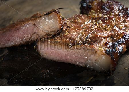 Sliced medium grilled steak on wood background.