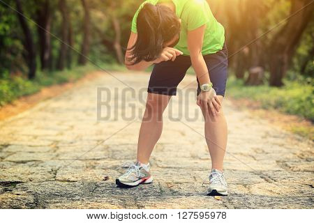tired woman runner taking a rest after running hard on forest trail