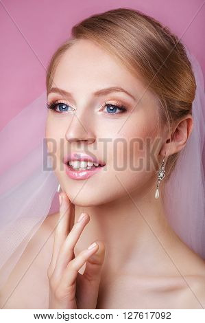 Young Gentle Quiet Bride in Classic White Veil. Portrait of beautiful bride. Beautiful Woman Touching her Face. Youth and Skin Care Concept. Beautiful woman with professional make up .