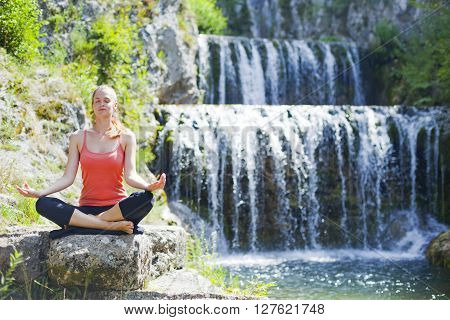Young women practise yoga by day in nature