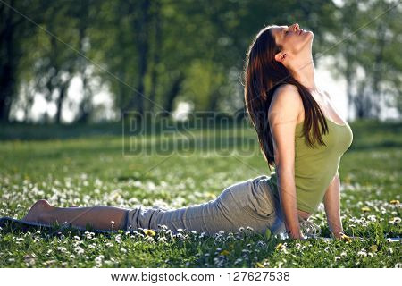 Young women practise yoga by day in nature