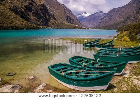 Huaraz, PERU in November 2015: Six green boats are waiting to be sailed across the blue glacier lagoon in the Peruvian Andes. Huaraz is a popular tourist destination for alpine hiking.