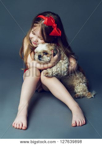 happy girl with her dog in the studio against grey background