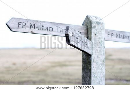 Under exposed Wooden sign post on moors at Malham Cove, Yorkshire, UK