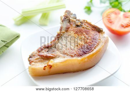 Roast pork in a bowl, morning and bokeh. On rostkoviana background, green cloth, half of tomato, slices of celery and parsley