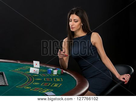 sexy woman with poker cards and chips. Female player in a beautiful black dress, throws a card. Two aces