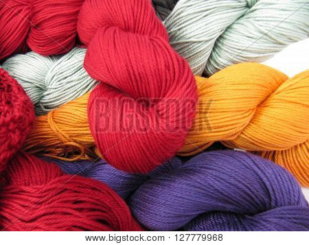 Different Colored yarn skeins piled up together.