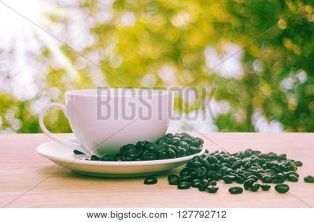 Roated coffee in a white cup of coffee on wooden with morning light background Vintage style