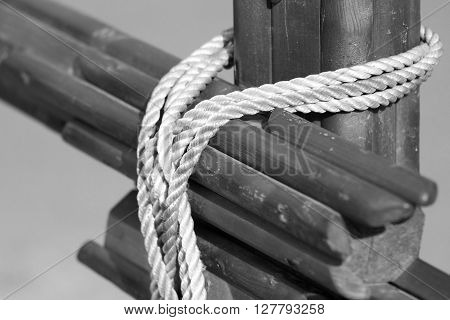 of monochrome tone closeup a design fragment from wooden logs fastened with a rope