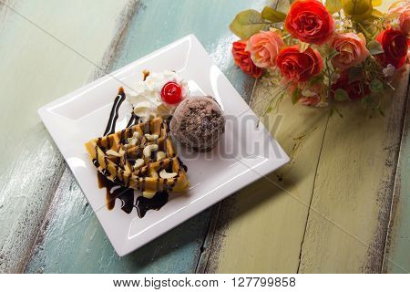 Sweet waffles with chocolate sauce and ice cream chocolate on color wood table