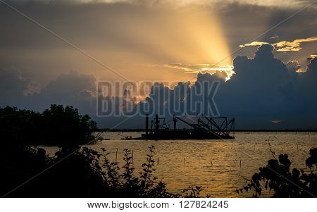 Boat dredging in Songkhla lake at the sunset time.