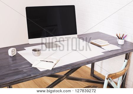 Sideview of wooden designer desktop with blank computer monitor and office tools on white brick background. Mock up