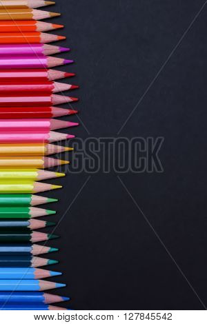 Colorful pencils on black background with text area