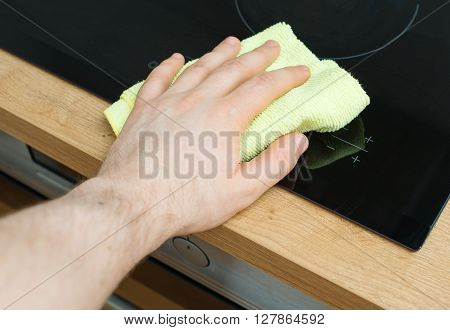 Man's Hand Wipes Cooktop In The Kitchen.