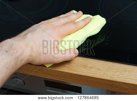 Man's Hand Wipes Cooktop In The Kitchen.