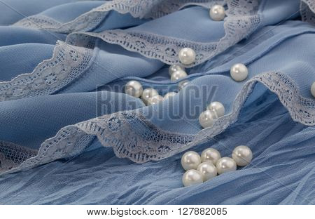 White pearls scattered on blue chiffon and lace background