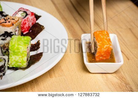 Sushi roll made dish. Sushi assorti on white plate with chopsticks nut souce glass of wine. Evening date closeup food photography