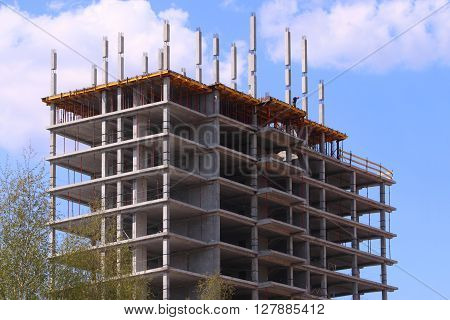 Big concrete residential building on construction site and pure blue sky with clouds