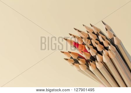 Celebratory pencil among usual pencils beige background
