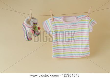 Baby laundry hanging on a clothesline beige background