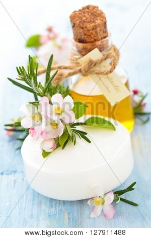 Soap with apple blossom and rosemary on old wooden table.