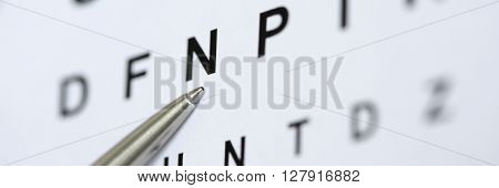 Silver ballpoint pen pointing to letter in eyesight check table. Sight test and correction excellent vision or optician shop laser surgery alternative driver health certificate examination concept
