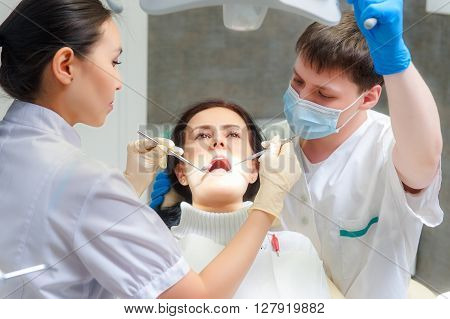 Female patient with open mouth examined by a dentist