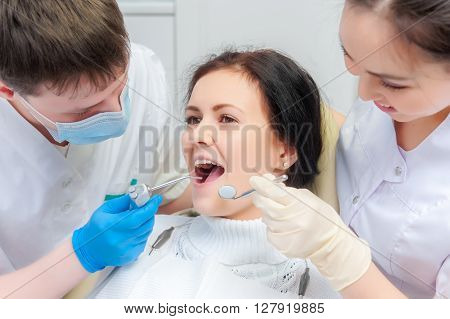 Female patient with open mouth examined by a dentist