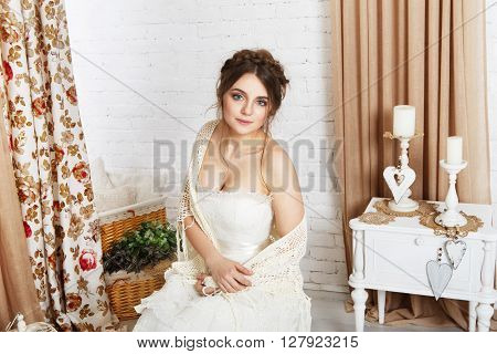 Wedding dress fashion. Beautiful young bride in vintage crochet shawl, shabby chic champagne color wedding dress. Rustic wedding dress at model, in decorated interior, studio shot, high key.