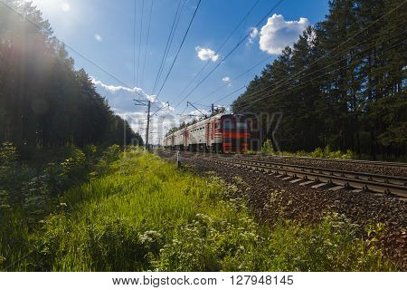Electric train goes by rail summer countryside sunny day
