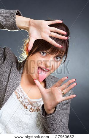 Image of a young business woman framing her face while having fun.