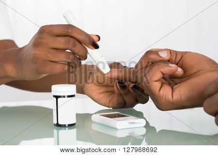 Close-up Of Hands Using Lancet On Finger Testing For Diabetes