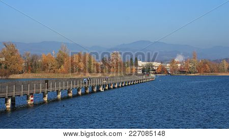 Timber Footbridge Connecting Rapperswil And Hurden. Lake Obersee, Reed And Golden Trees.