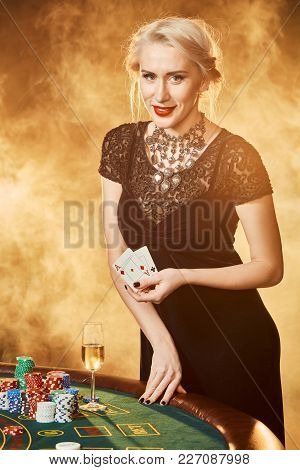 A Woman In A Black Dress With Cards In Her Hands Is Standing Near The Poker Table. On The Poker Tabl