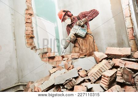 worker with demolition hammer breaking interior wall