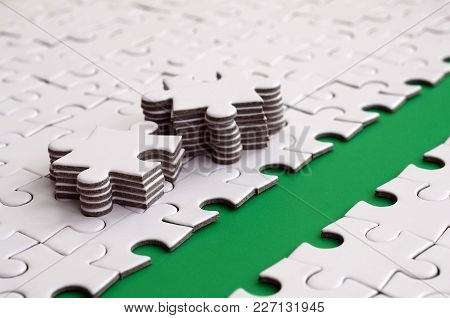 The Green Path Is Laid On The Platform Of A White Folded Jigsaw Puzzle. The Missing Elements Of The 
