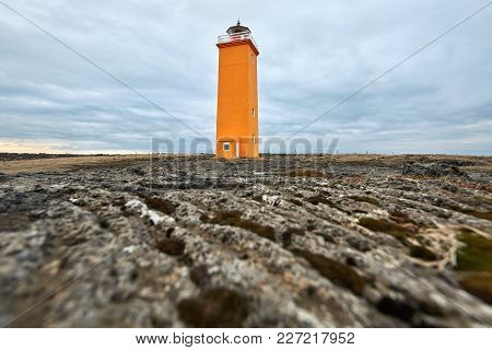 Colorful Orange Lighthouse On The Brown Field On The Background Of The Cloudy Sky On Reykjanes Penin