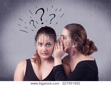 A teenager girl looking confused with drawn question marks above the head, while a girlfriend whispers something in her ear concept.
