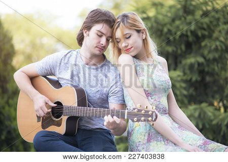 Young Cute Couple Enjoying Sunny Day, Boyfriend Playing Gutiar For His Girlfriend