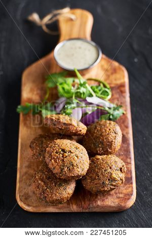 fresh fried vegan falafel with dipping suace on wooden bread board