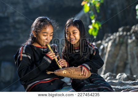 Daklak, Vietnam - Mar 9, 2017: Two Ede Ethnic Minority Little Girls Learning To Play The Flute In Fo