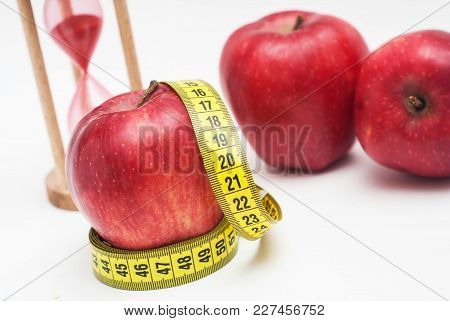 Close Up Red Apple With Measuring Metter And Sand Glass Clock On Background.