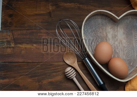 Kitchen Tools For Bakerry Or Cooking. Raw Eggs With Wooden Spooon, Orange Napkin, Heart Shape Box An