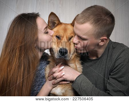 Man And Girl Kissing Funny Dog. The Concept Of Love For Animals, A Young Family And Pet