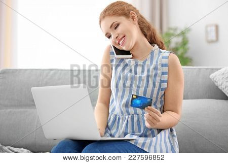 Young woman with credit card talking on phone. Online shopping