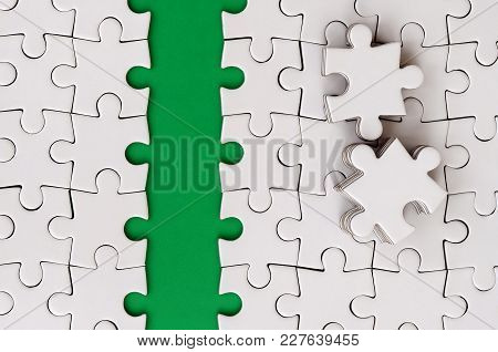 The Green Path Is Laid On The Platform Of A White Folded Jigsaw Puzzle. The Missing Elements Of The 