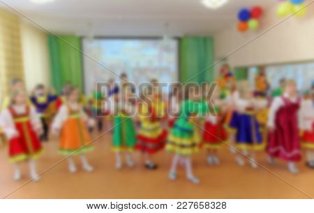 Folk Dances Of Children Theme Abstract Blur Background With Bokeh Effect. Children In Bright Folk Co